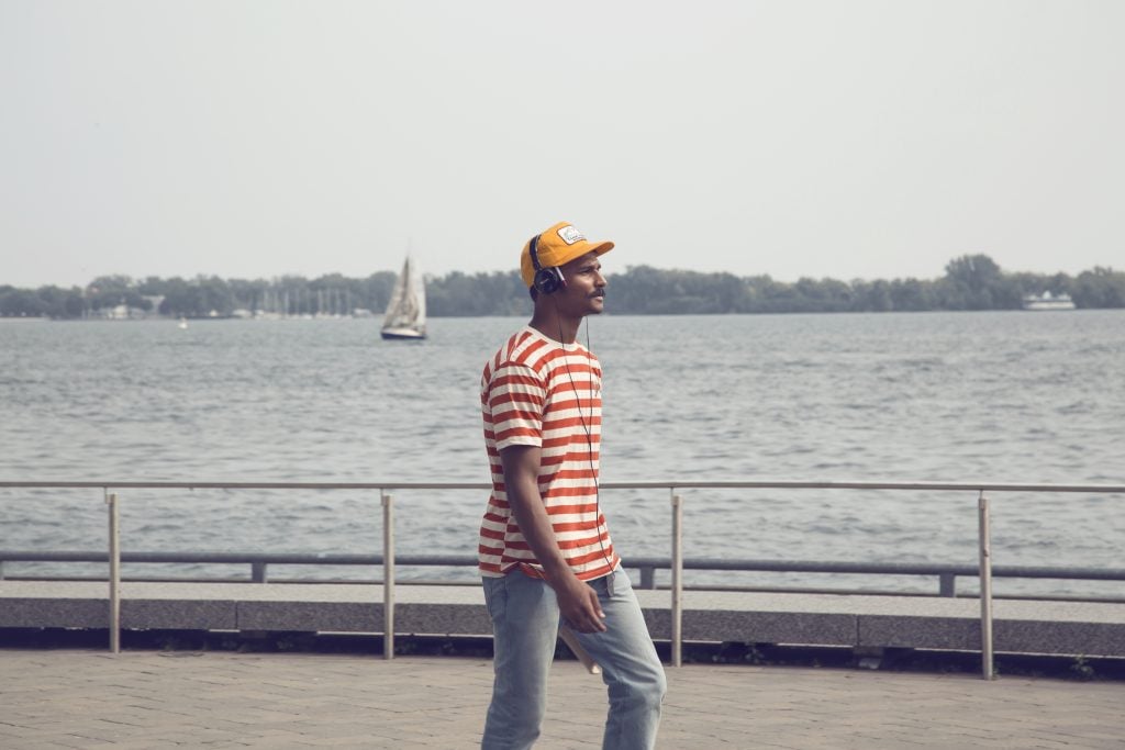 Man in striped shirt walking on dock in harbourfront, toronto
